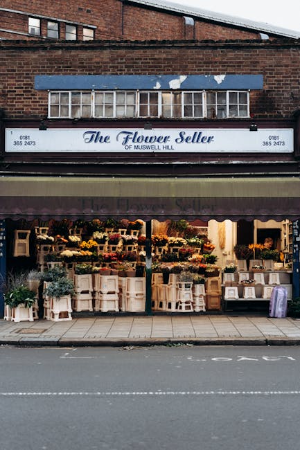 A florist shop named 'The Flower Seller of Muswell Hill' located on South Norwood High Street features a vibrant display of floral arrangements, with numerous bouquets and potted plants arranged on wh